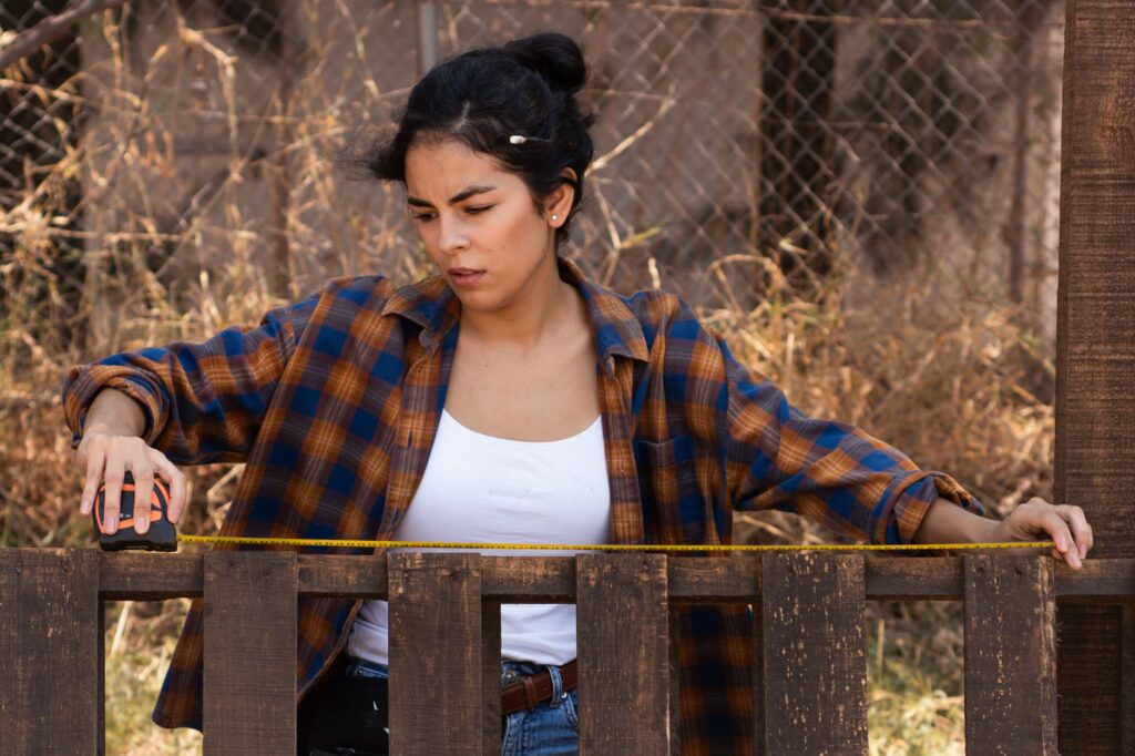 Woman measuring a wooden fence rail