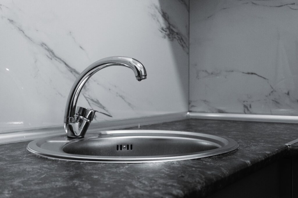Chrome kitchen faucet over a round steel sink