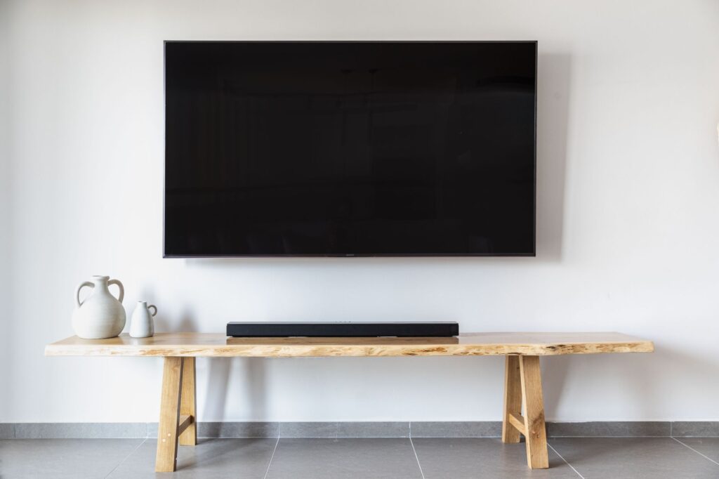 Flat screen TV mounted on a white wall over a wood console